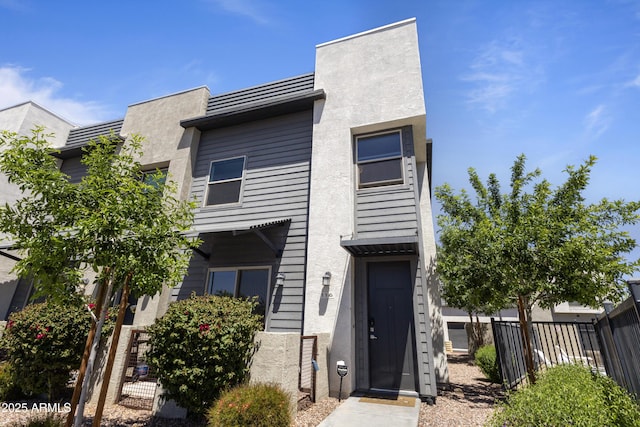 view of front facade with stucco siding and fence