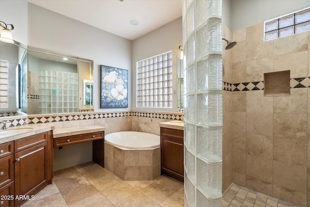 bathroom with independent shower and bath, tile walls, and vanity