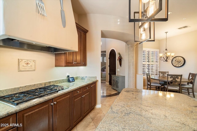 kitchen with light stone counters, light tile patterned flooring, stainless steel gas stovetop, and custom exhaust hood