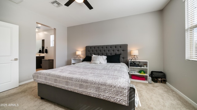 bedroom with light carpet, connected bathroom, multiple windows, and ceiling fan