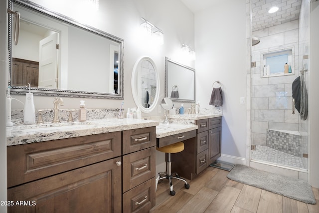 bathroom featuring baseboards, a shower stall, vanity, and wood finished floors