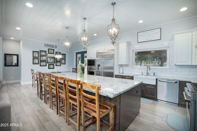 kitchen with white cabinets, decorative backsplash, a sink, and built in appliances