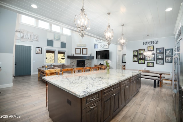 kitchen featuring light wood-type flooring, a healthy amount of sunlight, dark brown cabinets, and a kitchen bar