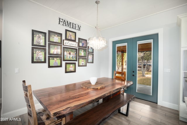 dining space featuring baseboards, wood finished floors, and french doors