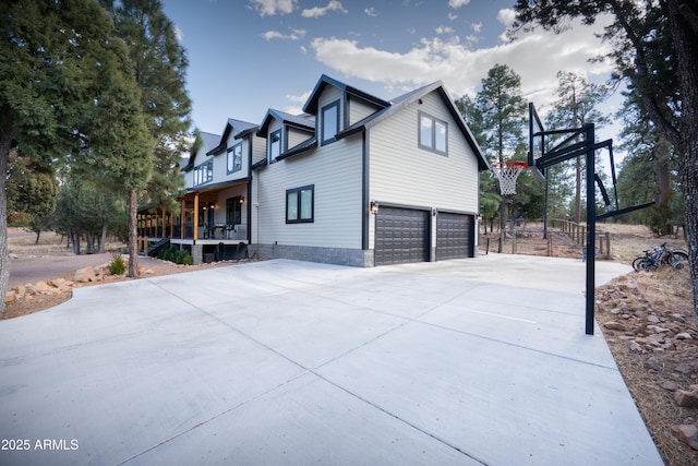 view of property exterior featuring a garage, concrete driveway, and covered porch