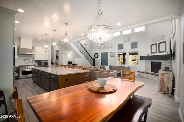 dining space featuring dark wood finished floors, wooden ceiling, stairs, a fireplace, and a chandelier