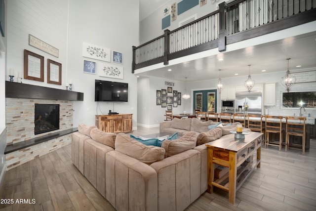 living room with french doors, a fireplace, recessed lighting, a high ceiling, and wood finished floors