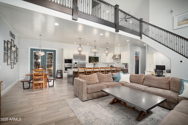 living room with stairway, recessed lighting, light wood-style flooring, and a high ceiling