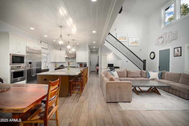 living room with a notable chandelier, light wood finished floors, stairway, and recessed lighting