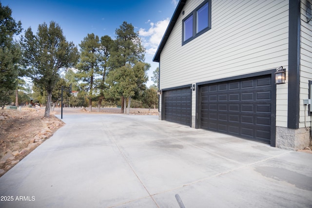 view of property exterior with an attached garage and concrete driveway