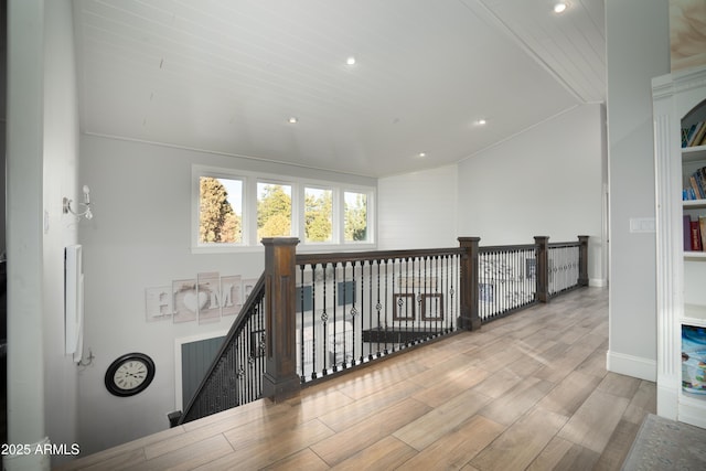 hall featuring baseboards, wood finished floors, vaulted ceiling, an upstairs landing, and recessed lighting