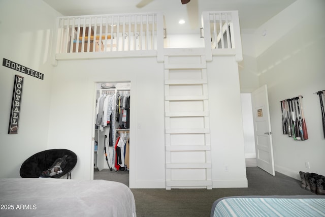 bedroom with a high ceiling, baseboards, a closet, dark carpet, and a walk in closet