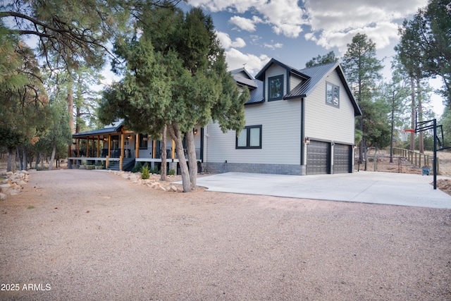 view of front of house featuring covered porch, metal roof, driveway, and an attached garage