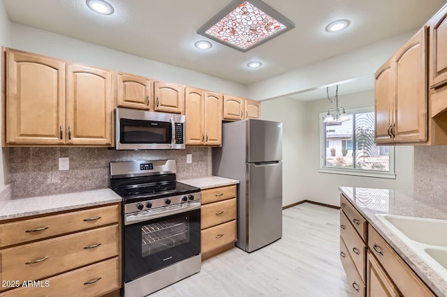 kitchen featuring light wood-style flooring, a sink, stainless steel appliances, light brown cabinets, and backsplash