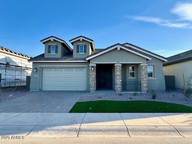 view of front of property with an attached garage, driveway, stone siding, and fence