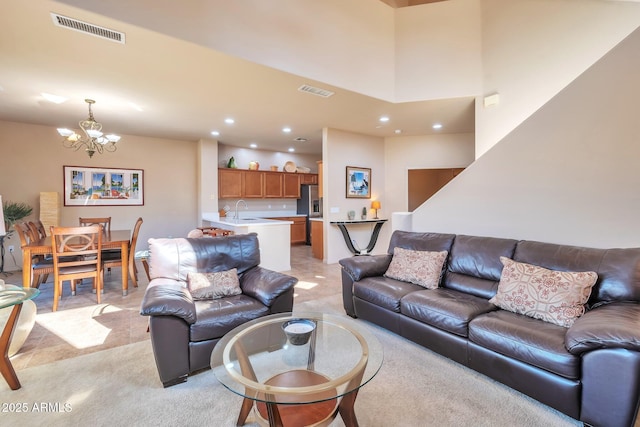 living area featuring light carpet, recessed lighting, visible vents, and a notable chandelier