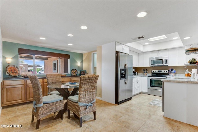 kitchen featuring light tile patterned floors, stainless steel appliances, sink, and white cabinetry