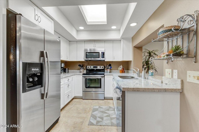 kitchen with white cabinetry, appliances with stainless steel finishes, kitchen peninsula, light tile patterned flooring, and sink