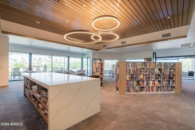 kitchen with dark carpet, a center island, a tray ceiling, and wooden ceiling