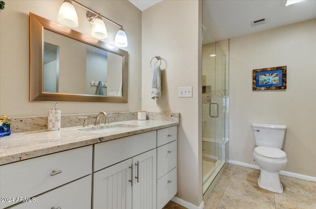 bathroom with a shower with shower door, vanity, tile patterned flooring, and toilet