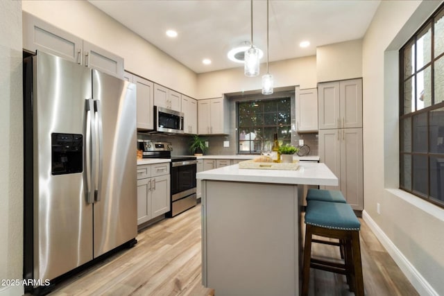 2110 W Navarro Ave, Mesa, AZ 85202 - kitchen featuring stainless steel appliances, light wood-type flooring, decorative backsplash, light countertops, and a center island