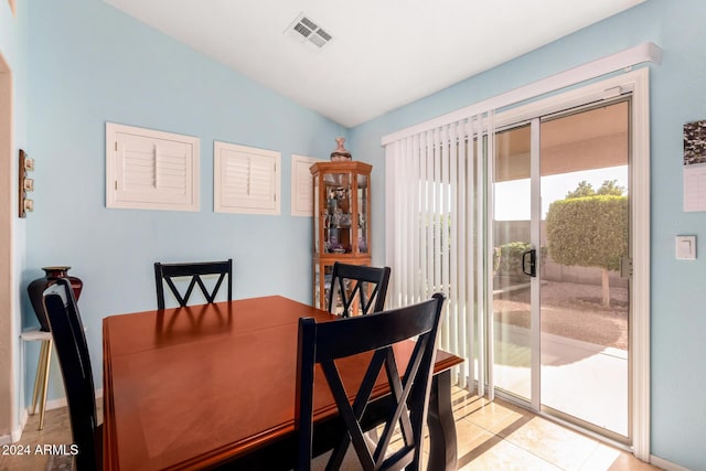 tiled dining room featuring vaulted ceiling