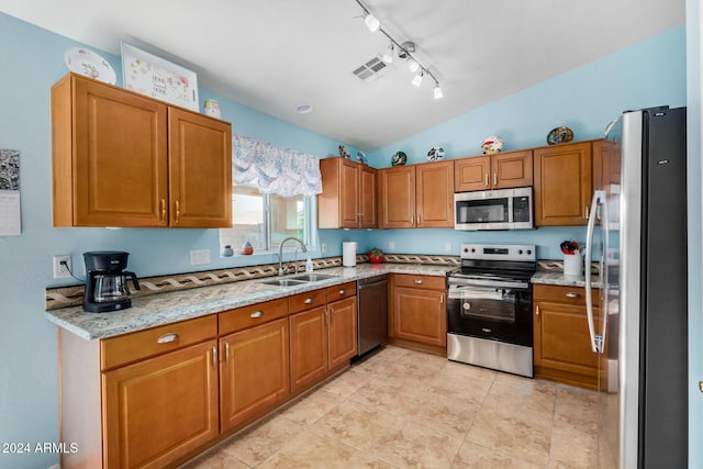 kitchen featuring sink, vaulted ceiling, appliances with stainless steel finishes, light tile patterned flooring, and light stone counters