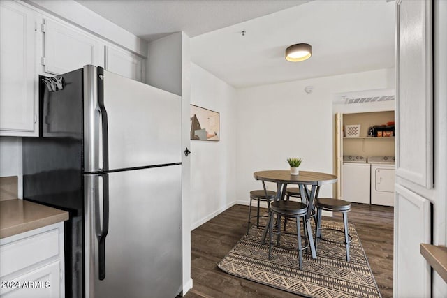 kitchen featuring washing machine and clothes dryer, stainless steel refrigerator, white cabinets, and dark hardwood / wood-style floors