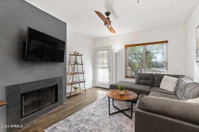 living room featuring hardwood / wood-style floors, ceiling fan, a wealth of natural light, and a tiled fireplace