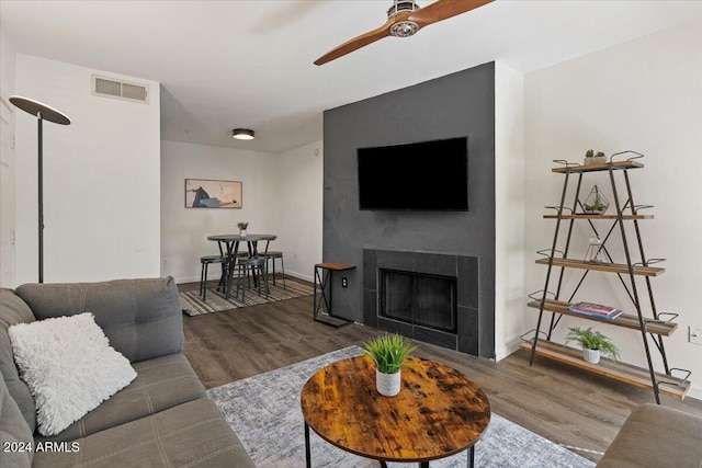 living room featuring a large fireplace, ceiling fan, and dark hardwood / wood-style flooring