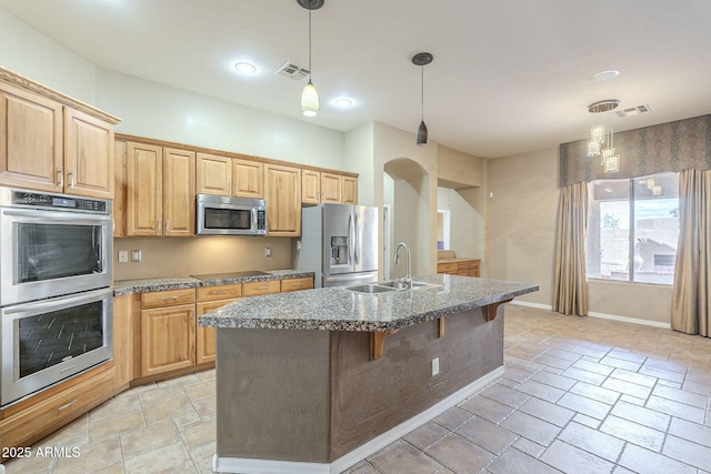 kitchen with a kitchen bar, visible vents, an island with sink, a sink, and stainless steel appliances