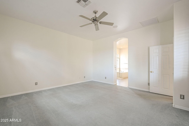 unfurnished room with carpet, baseboards, visible vents, arched walkways, and ceiling fan