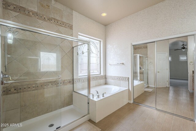 bathroom with ceiling fan, wood finished floors, a garden tub, and a stall shower