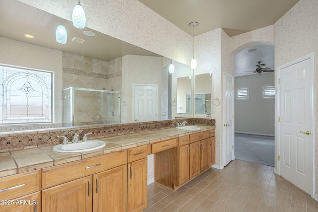 bathroom featuring a sink, double vanity, ceiling fan, and a shower stall