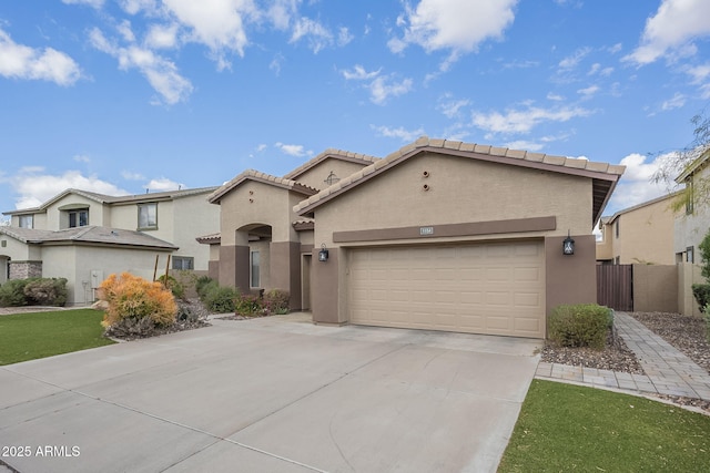 mediterranean / spanish home with stucco siding, concrete driveway, a garage, and fence