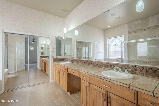 bathroom with a shower stall, double vanity, visible vents, and a sink