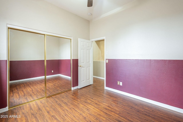 unfurnished bedroom with ceiling fan, a closet, baseboards, and wood finished floors