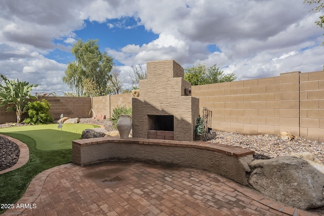 view of patio / terrace featuring an outdoor stone fireplace and a fenced backyard