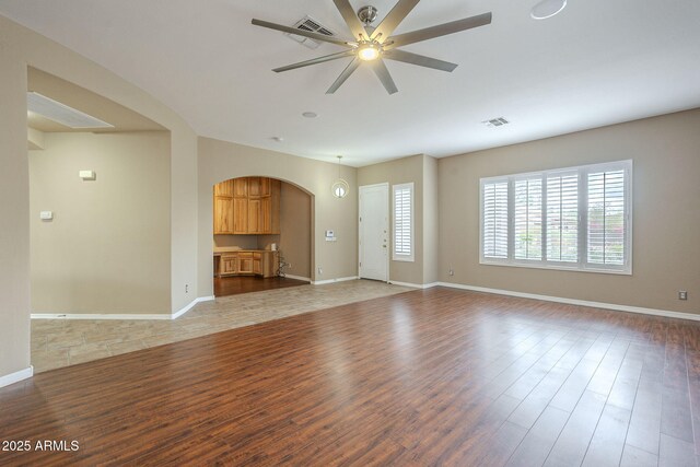 unfurnished living room with ceiling fan, visible vents, baseboards, and light wood-style flooring