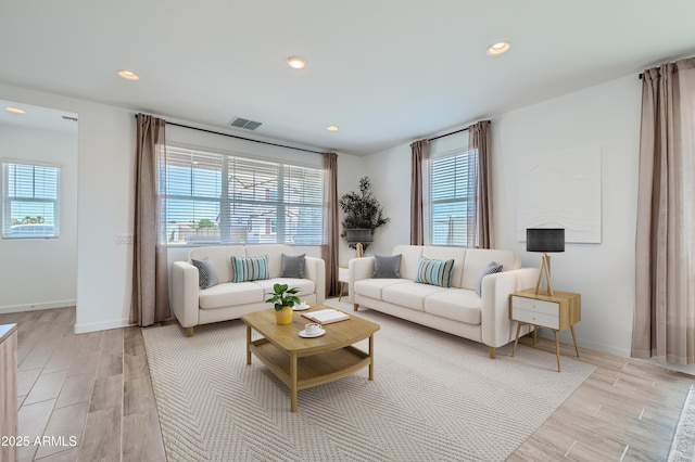 living area featuring light wood-style flooring, recessed lighting, visible vents, and baseboards