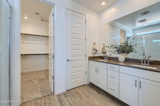 bathroom with a sink, visible vents, wood finish floors, and a spacious closet