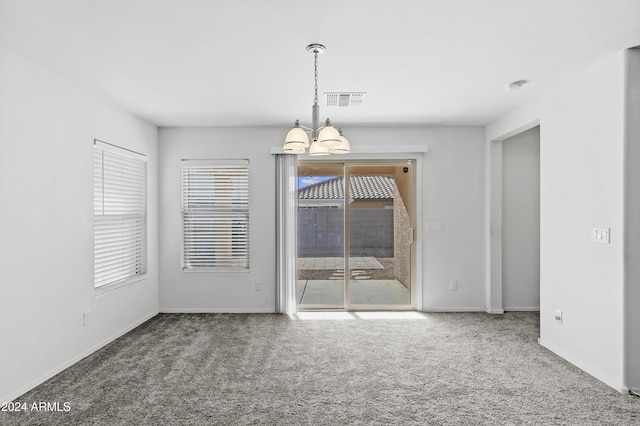 unfurnished dining area with carpet floors and an inviting chandelier