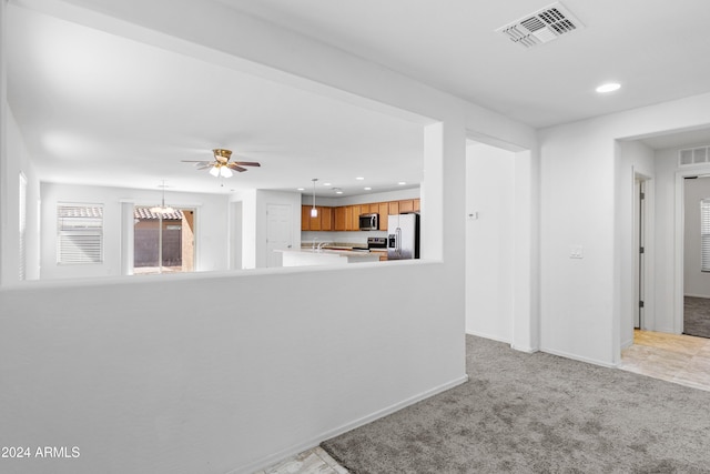 interior space with ceiling fan with notable chandelier, light colored carpet, and sink