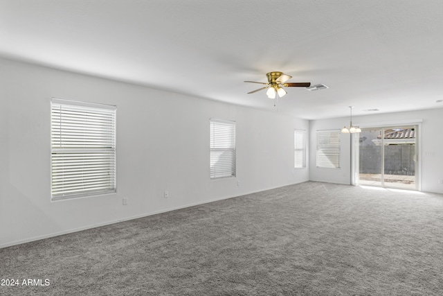 empty room with carpet flooring and ceiling fan with notable chandelier