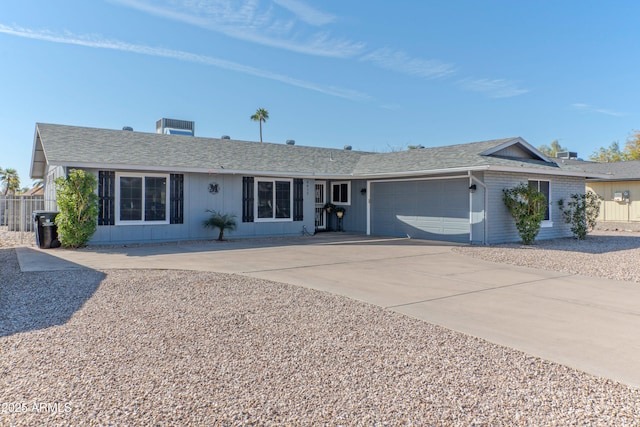 single story home with a garage, concrete driveway, roof with shingles, and fence