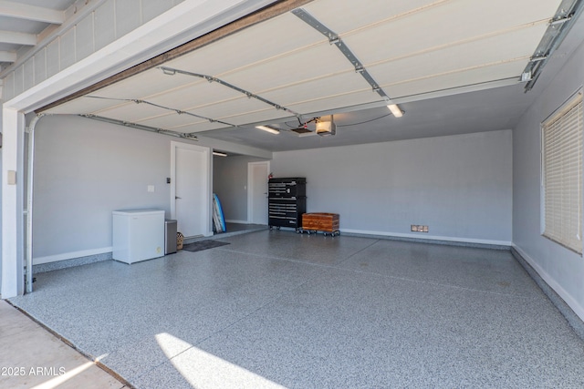 garage with a garage door opener, fridge, and baseboards