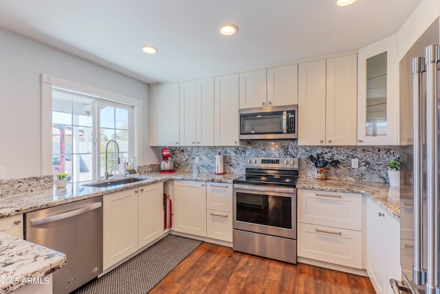 kitchen featuring dark wood-style flooring, stainless steel appliances, tasteful backsplash, white cabinetry, and a sink