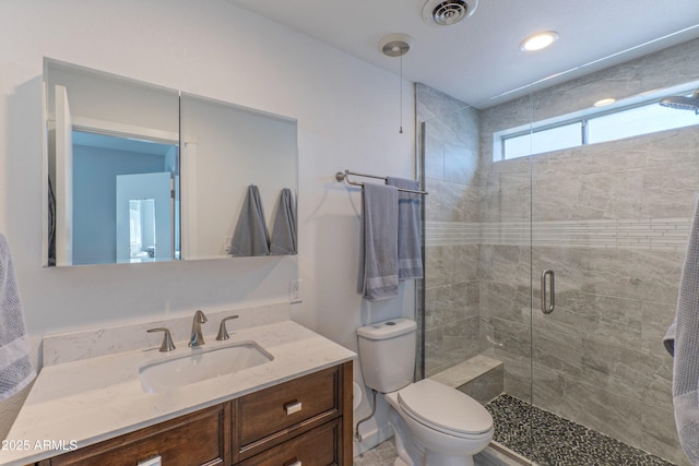 full bath featuring toilet, a stall shower, vanity, and visible vents