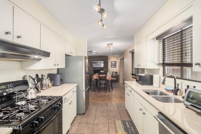 kitchen with white cabinets, rail lighting, sink, appliances with stainless steel finishes, and light tile patterned floors