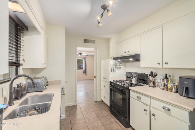 kitchen with white cabinetry, rail lighting, light tile patterned floors, black range with gas stovetop, and sink